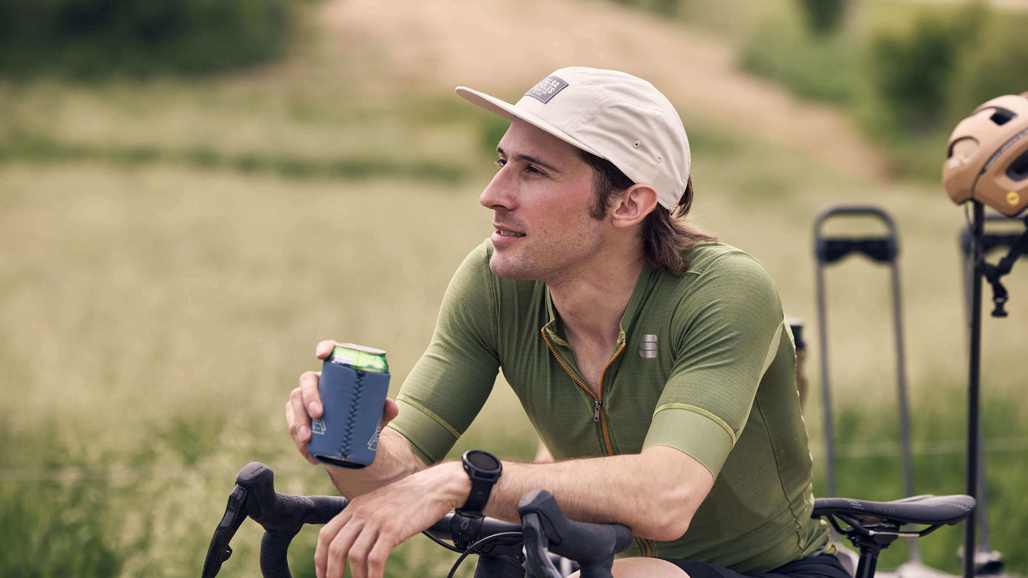 A rider sits over his bike while wearing the Salsa Adventure by Bike Hat in cream.