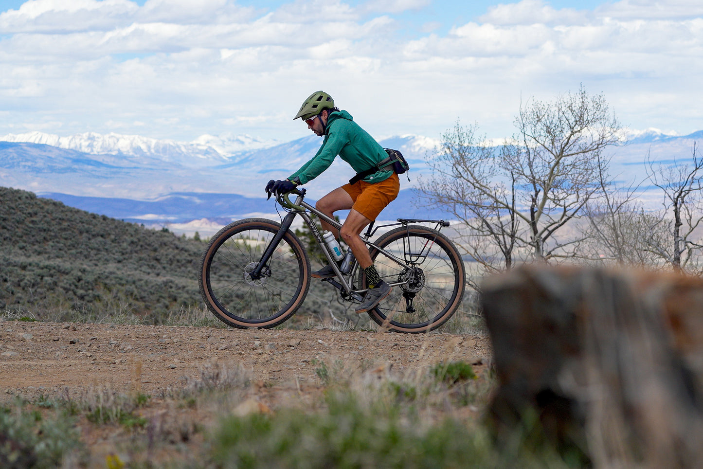 Cyclist biking on a gravel trail in a scenic outdoor setting with mountains in the background
