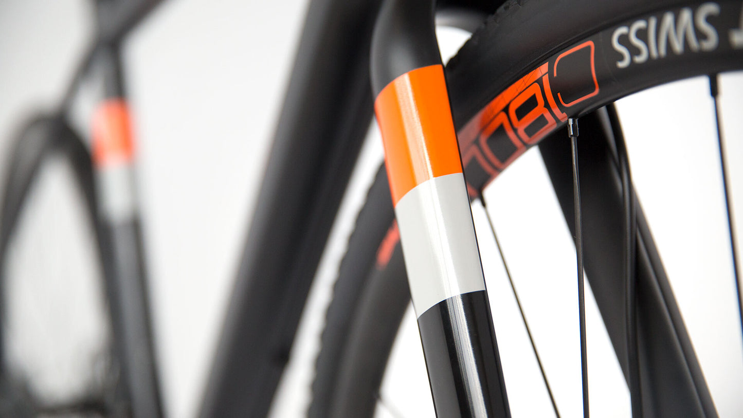 Close-up of a bicycle fork with orange and white accents on a blurred background