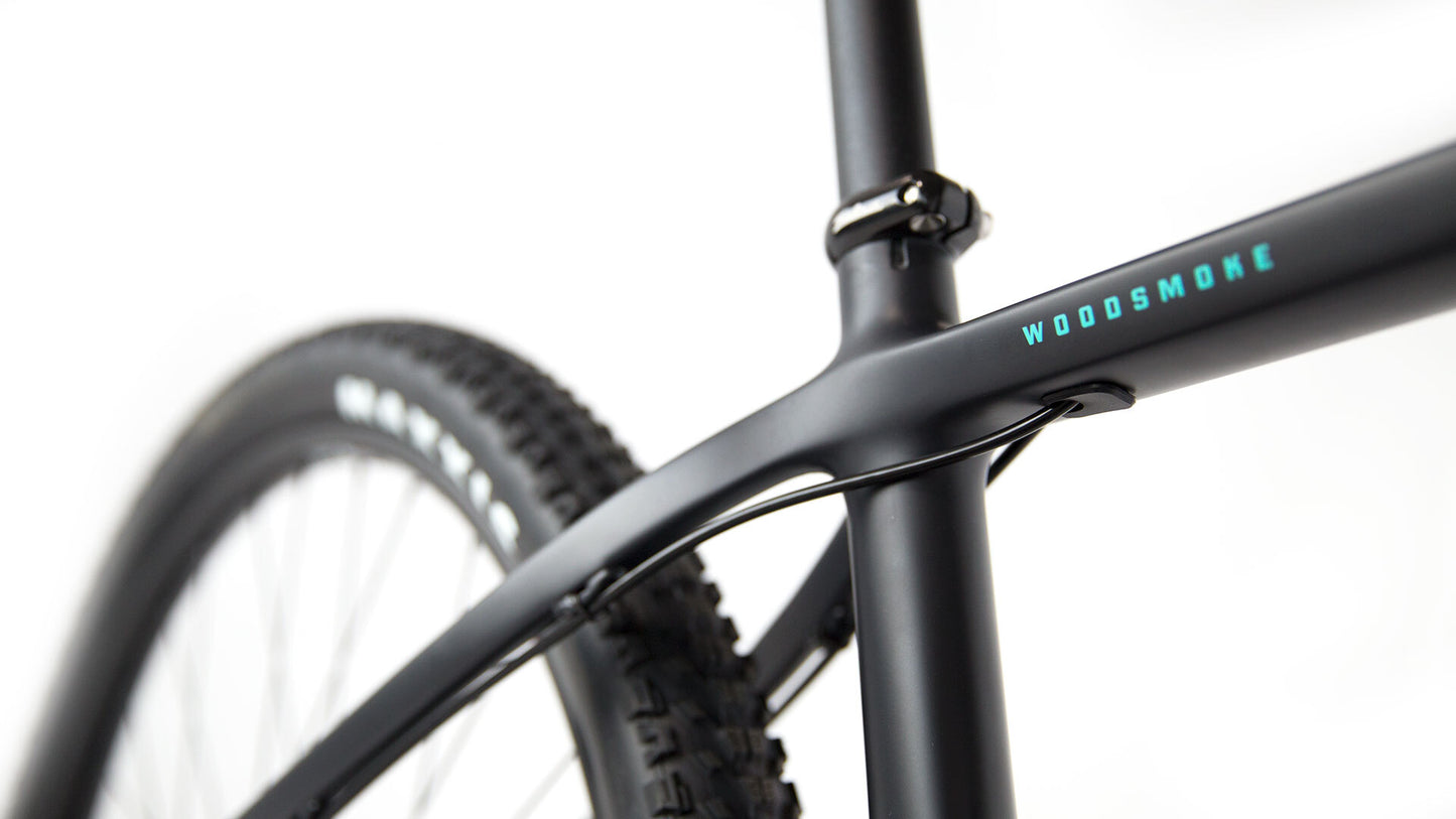 Close-up of a bicycle frame with 'Woodsmoke' branding on a white background