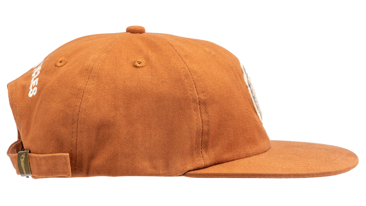 A rust-orange cotton flat-brim cap featuring a small embroidered patch of a pepper on the front - side view