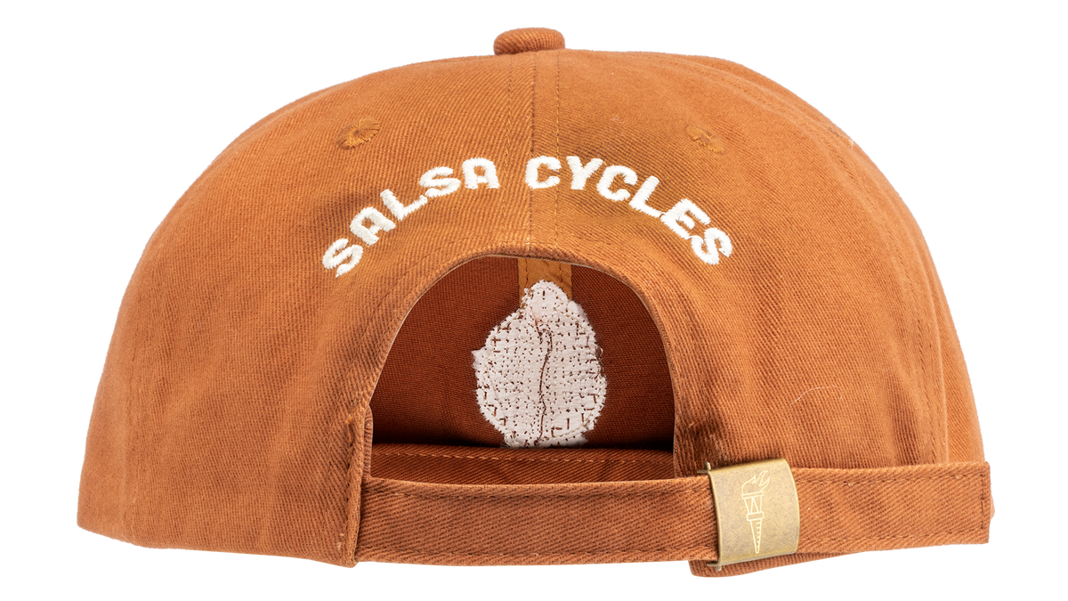 A rust-orange cotton flat-brim cap featuring 'Salsa Cycles' on the back