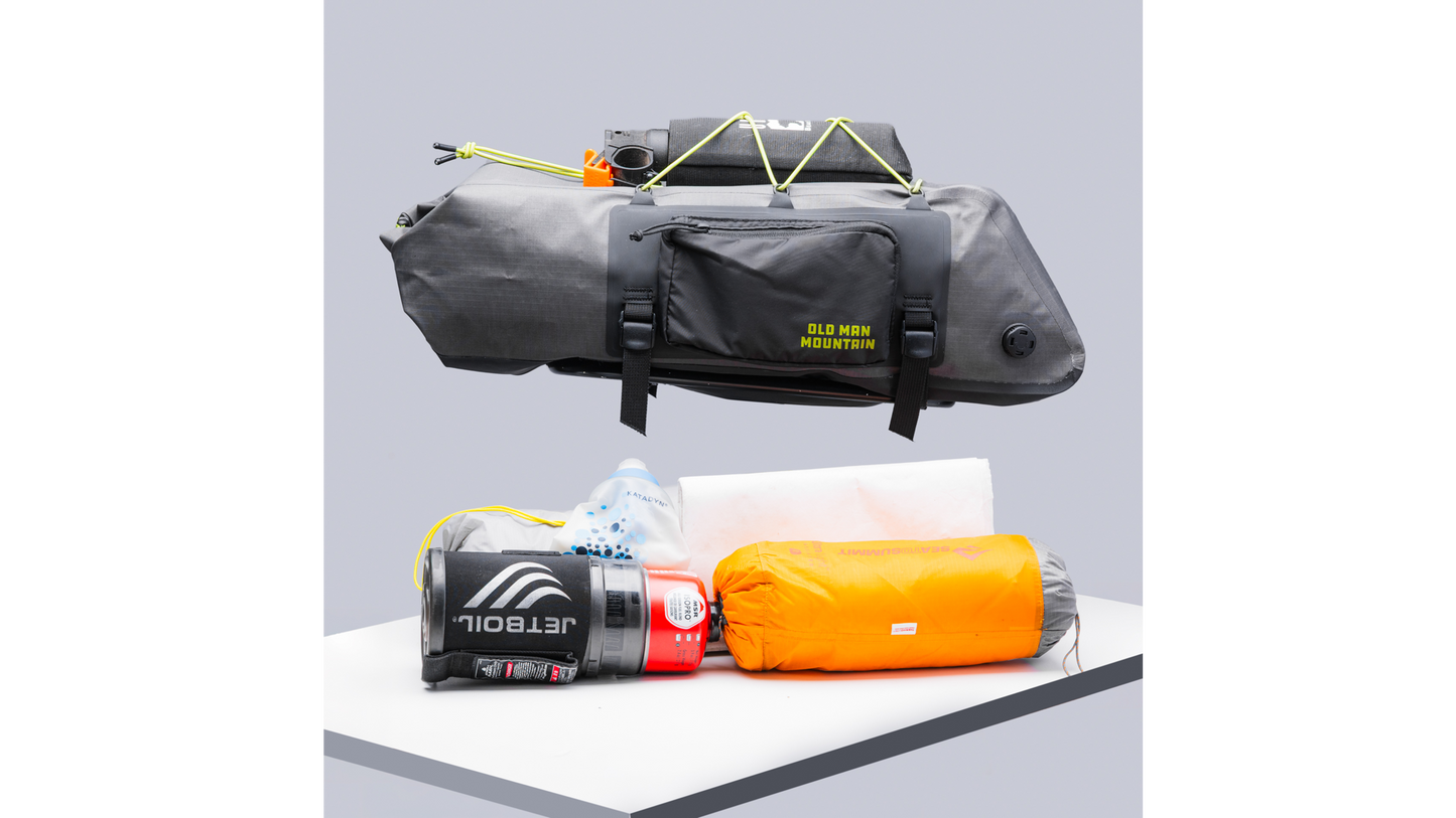 An Old Man Mountain Atlas Rack Pack, shown above all the gear that can fit inside, such as a canteen and sleeping bag.
