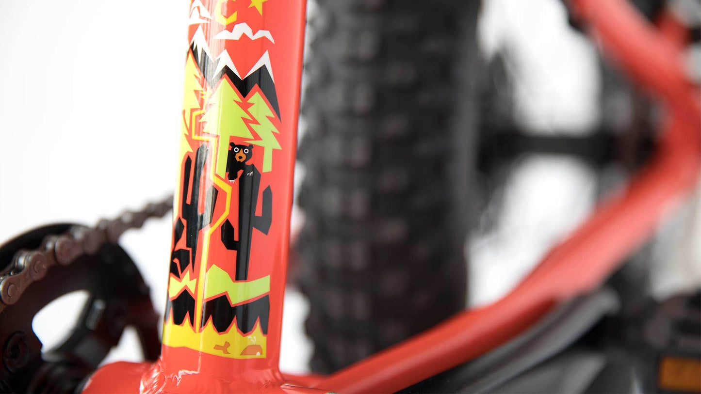 Close-up of a red bicycle frame with colorful graphics on a blurred background
