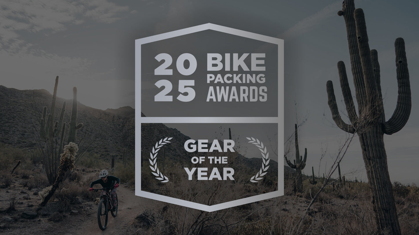 2025 Bikepacking Awards - Gear of the Year 2025 Winner - Salsa Spearfish Mountain Bike. In the background a cyclist rides their Spearfish through a desert landscape.