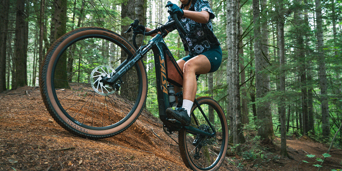 Person riding a Salsa Wanderosa ebike uphill on a trail in a forest