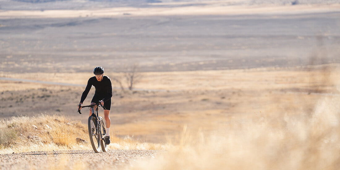 Person cycling on a dirt road in a desert landscape