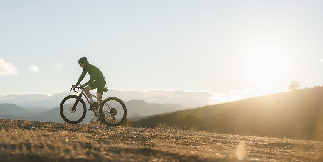 Person riding a mountain bike on a hill with a scenic background