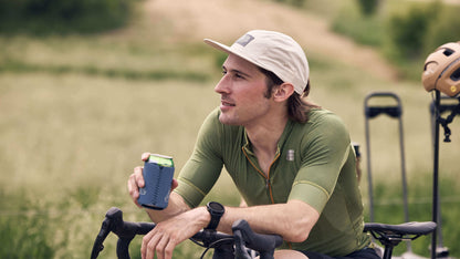A rider sits over his bike while wearing the Salsa Adventure by Bike Hat in cream.