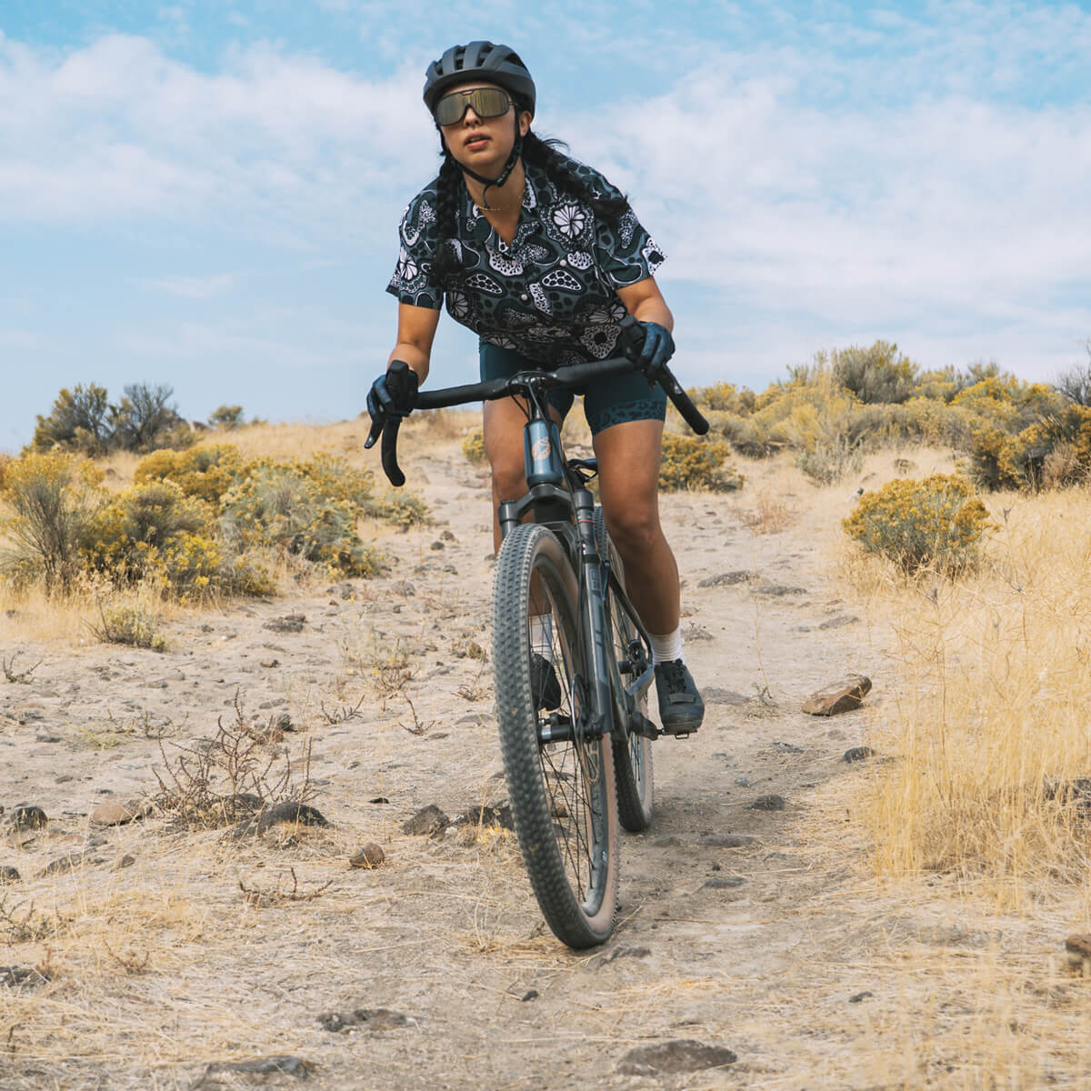 Cyclist riding a Salsa Wanderosa ebike on a desert trail with a clear blue sky.