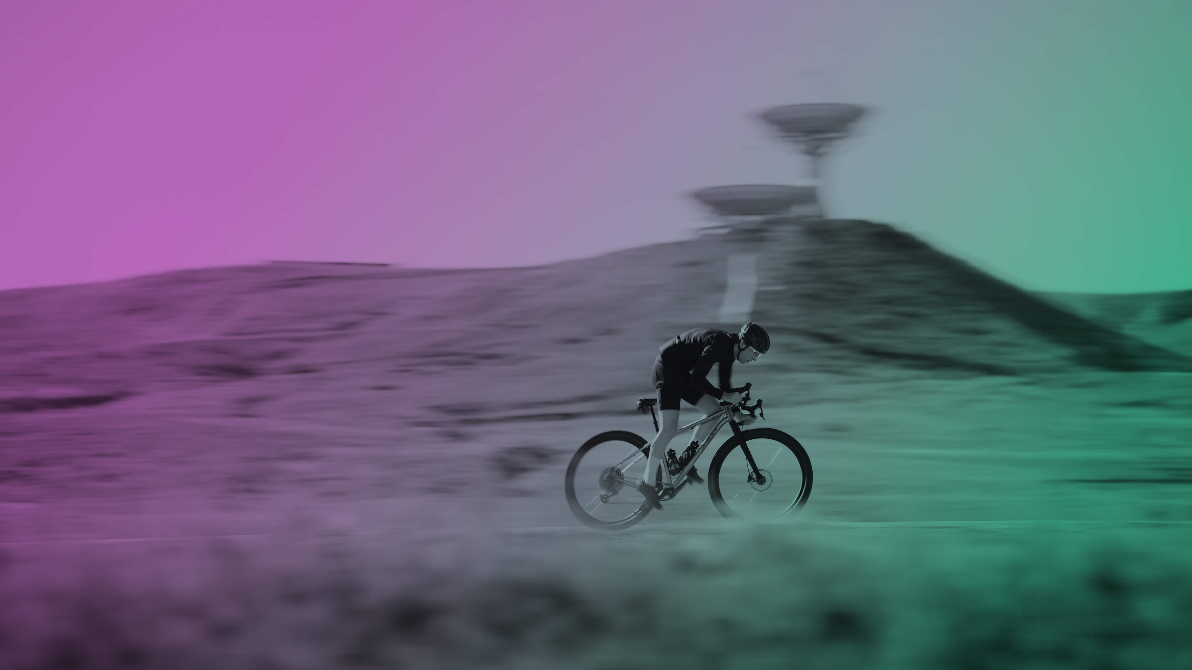A cyclist rides a Salsa Fargo 32 gravel bike across a desert landscape with a pink-to-green color-graded filter and a blurred futuristic structure in the background.