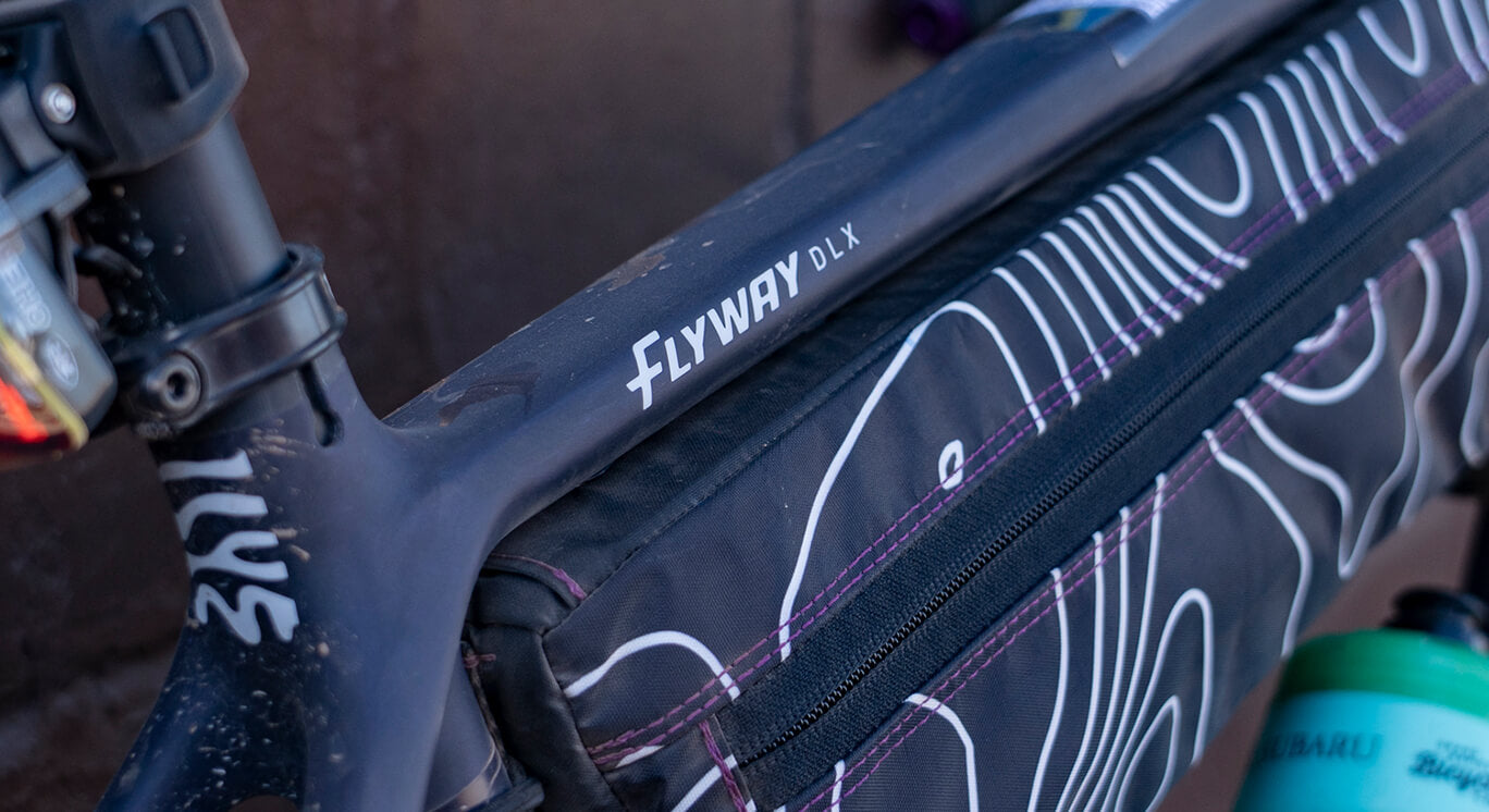 Close-up of a bicycle frame with 'Flyway' branding and bag mounted to the frame.