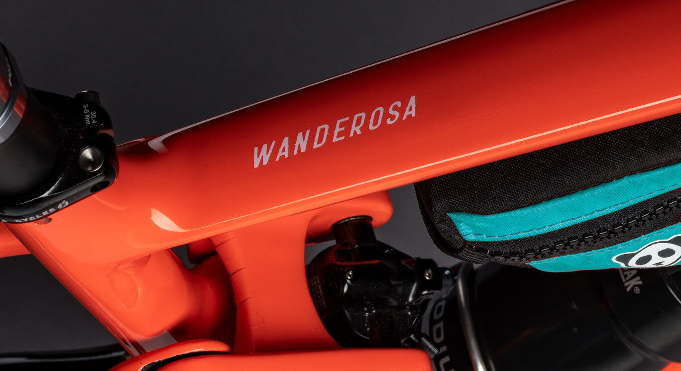 Close-up of an orange bike frame with a 'Wanderosa' branding decal