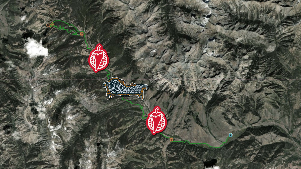 A satellite map view of a rugged mountain terrain with green and blue route lines and red leaf-shaped icons marking points of interest.