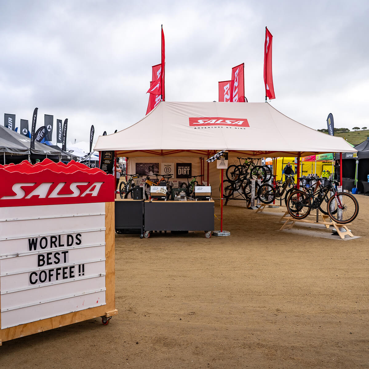 Salsa bike booth with bicycles and a sign advertising 'Worlds Best Coffee' at an outdoor event.