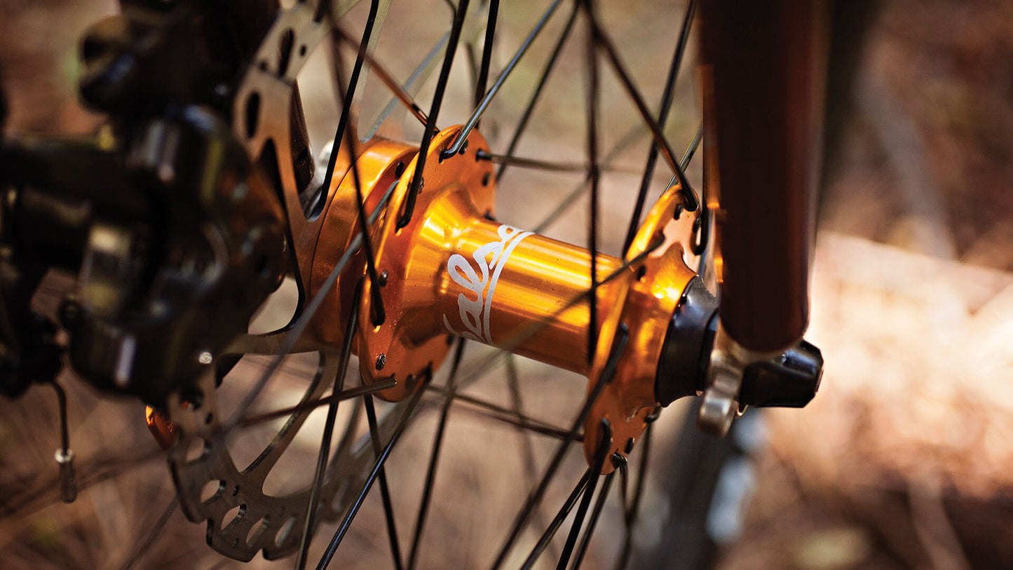 Close-up of a bicycle hub with orange finish and blurred background
