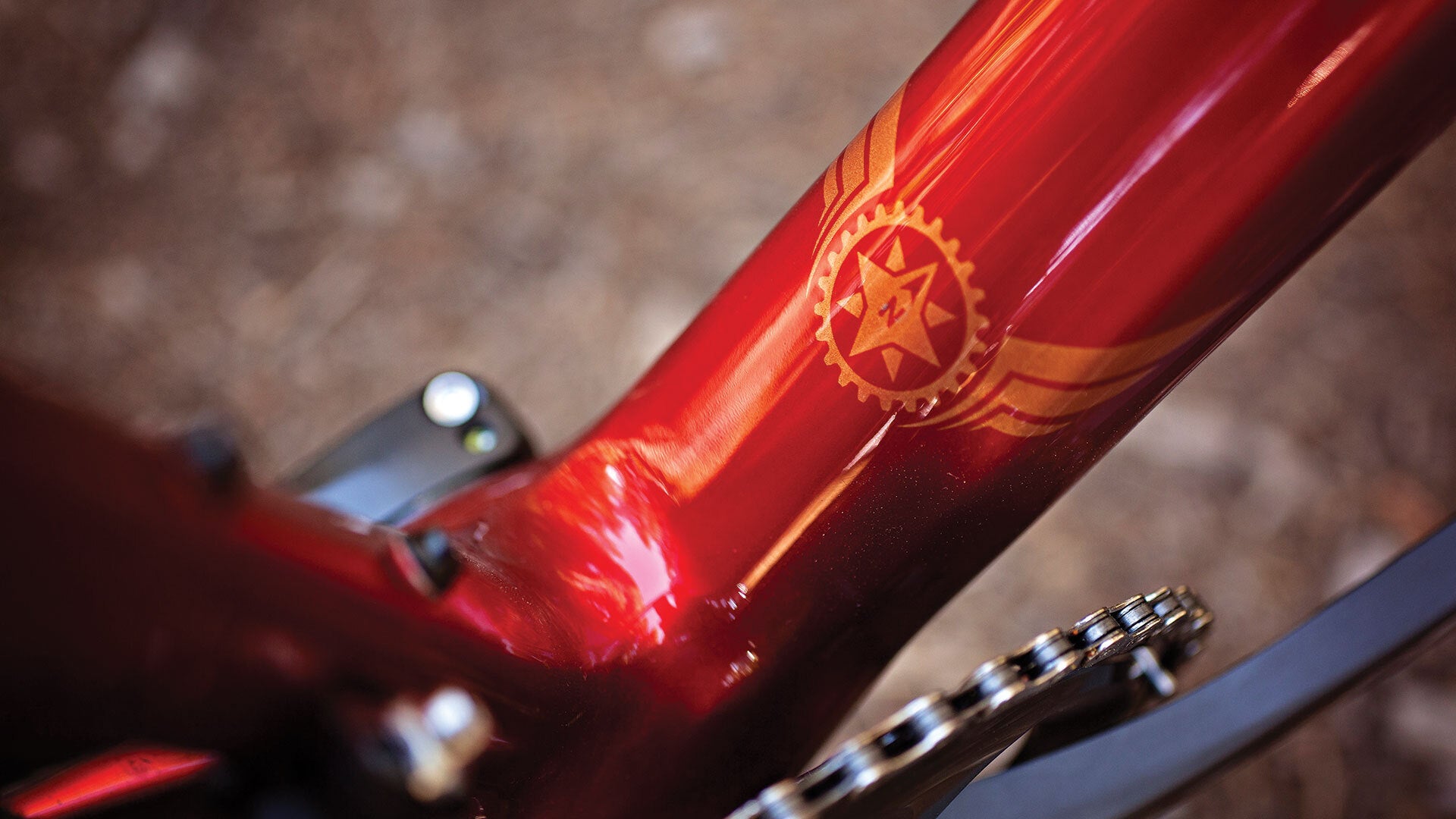 Close-up of a red bicycle frame with a star and gear design.