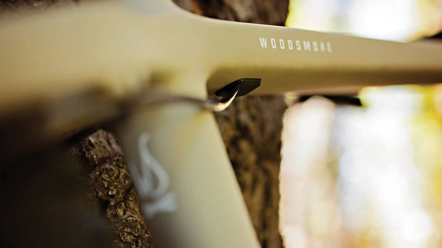 Close-up of a wooden tool with 'WOODSMAN' branding, blurred natural background