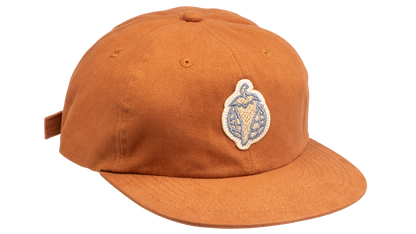 A rust-orange cotton flat-brim cap featuring a small embroidered patch of a pepper on the front