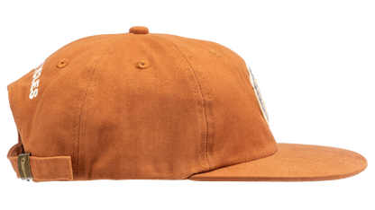 A rust-orange cotton flat-brim cap featuring a small embroidered patch of a pepper on the front - side view