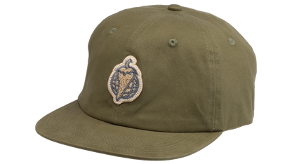 An olive green flat-brim baseball cap featuring a circular embroidered patch on the front with a pepper