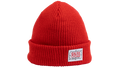 A bright red ribbed knit beanie hat with a folded cuff, featuring a white rectangular patch on the front that reads 'SALSA CYCLES' 